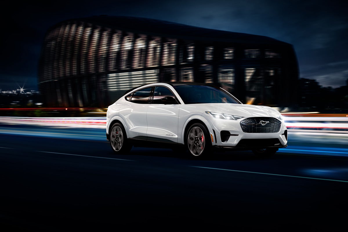A Mustang Mach-E® driving down a city road at night.